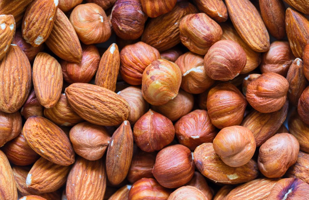 Nuts pile background. Keto diet-friendly foods like cashew, almond, hazelnut mix closeup. Organic food rustic banner template. Tasty healthy snack. Scattered nut on table top view. Nut assortment flat lay. Nut texture. Nut package;