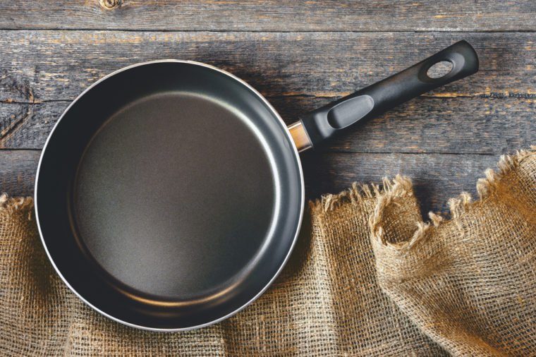 An empty pan on a wooden table and tablecloth