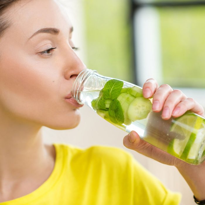 Close-up of a woman drinking water with mint, cucumber and lime during a workout with dumbbells. Detox dieting concept; Shutterstock ID 622941011; Job (TFH, TOH, RD, BNB, CWM, CM): Taste of Home