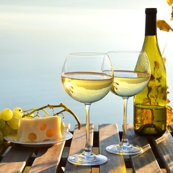 white wine and grapes against vineyards