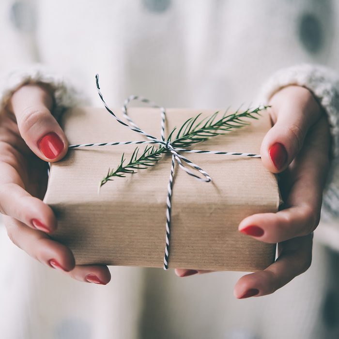 Woman's hands hold christmas or new year decorated gift box.