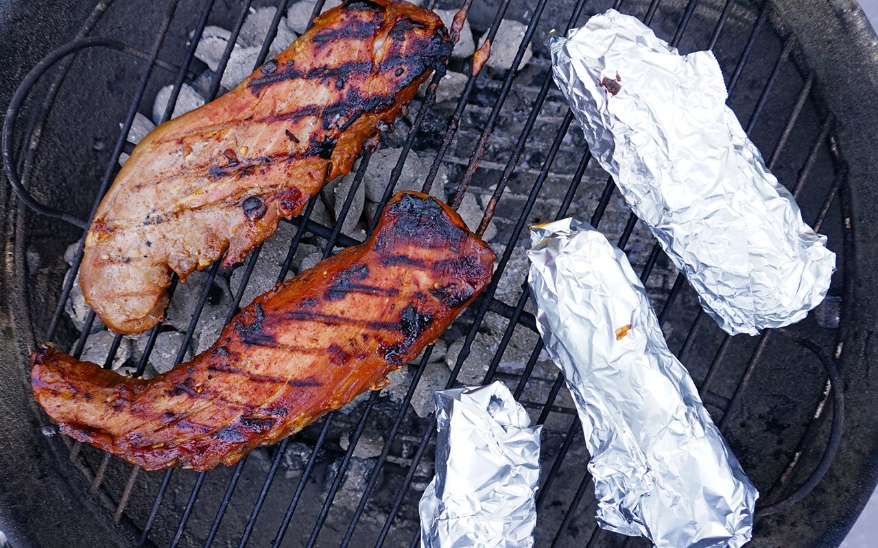 pork tenderloin on a grill with roasted corn on the cob
