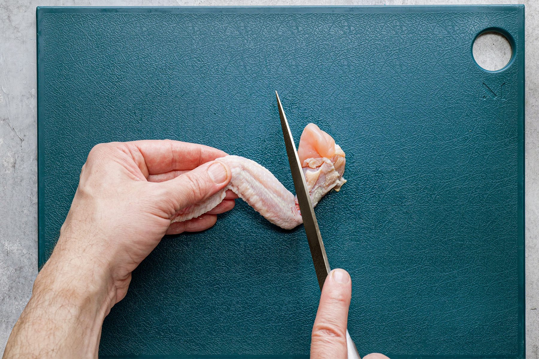 A person is cutting chicken wing with Sharp Knife